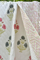Floral and geometric patterned fabric with pink flowers and green leaves on a white background.