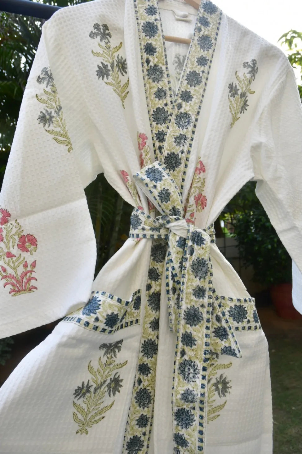 White kimono-style rove with floral embroidery and a tied belt, outdoors.