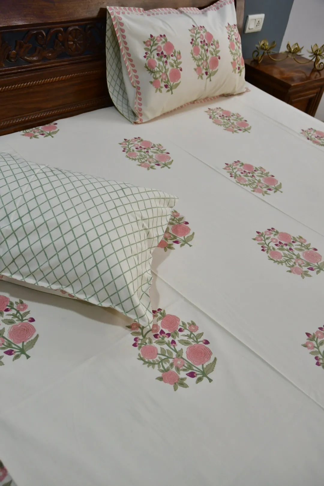 Floral embroidered bedsheet on a bed with matching pillows.