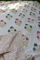 Floral patterned quilt with a folded corner on a white background