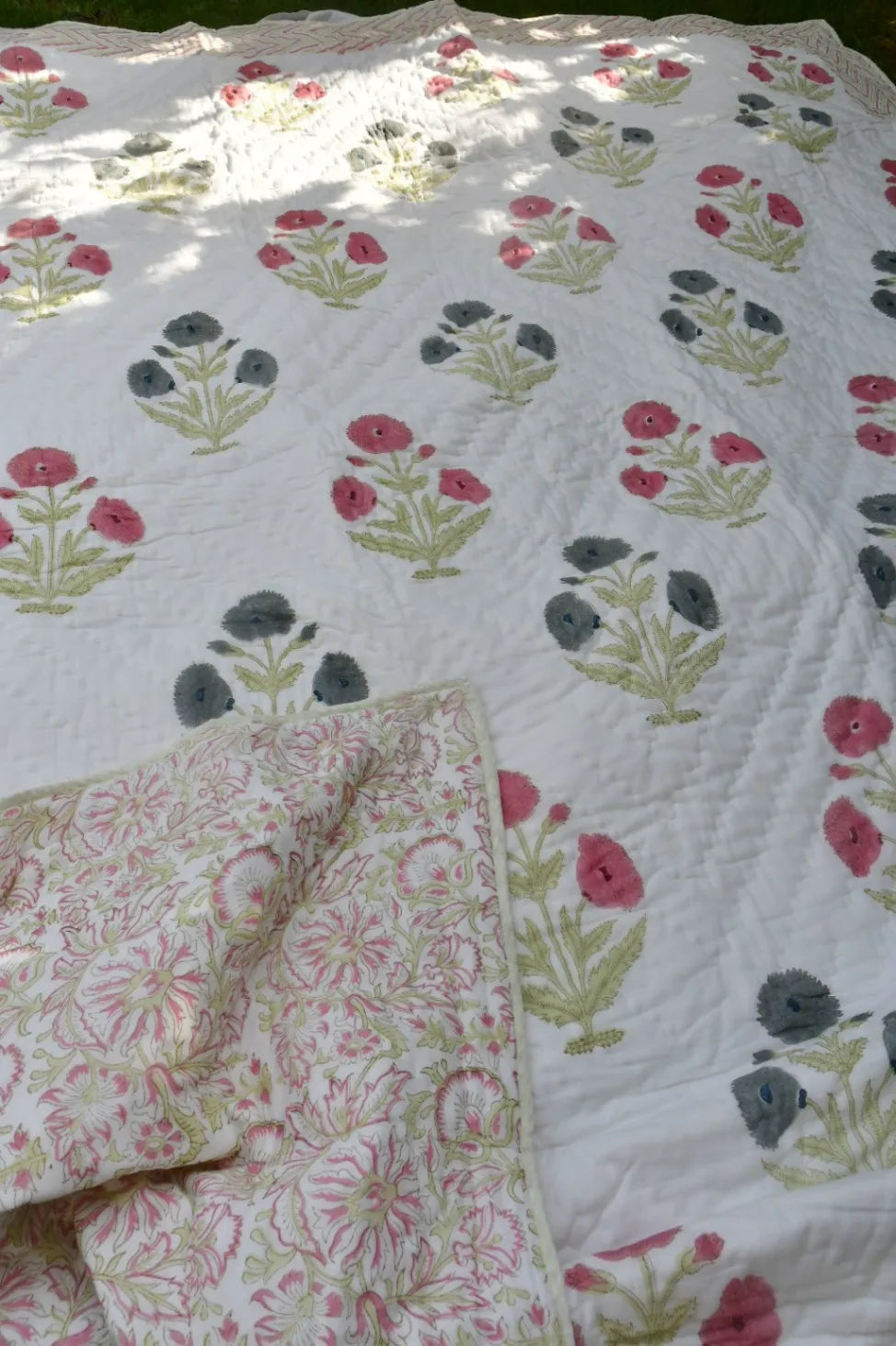 Floral patterned quilt with a folded corner on a white background