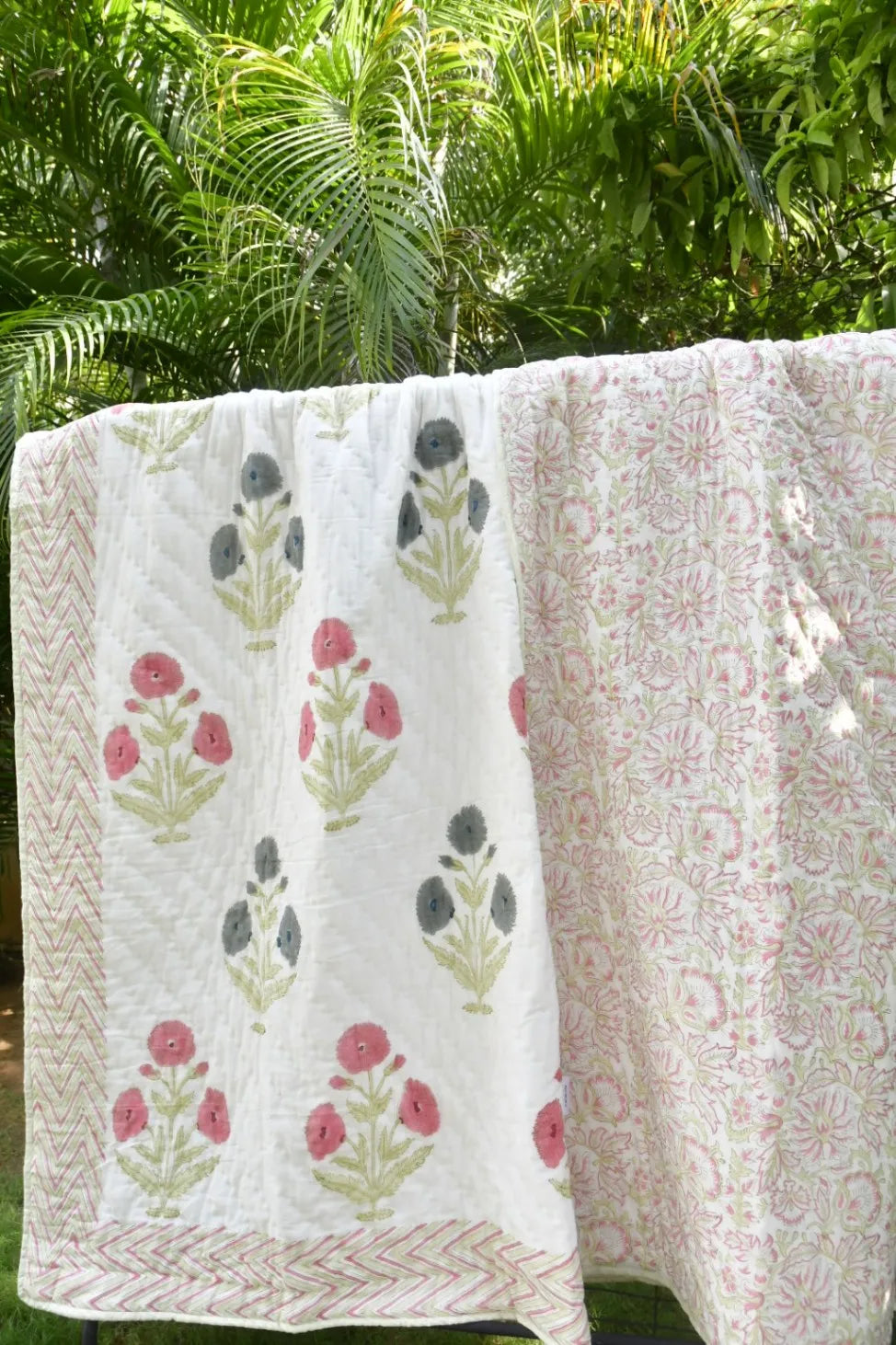 Floral patterned quilt draped over a chair with greenery in the background