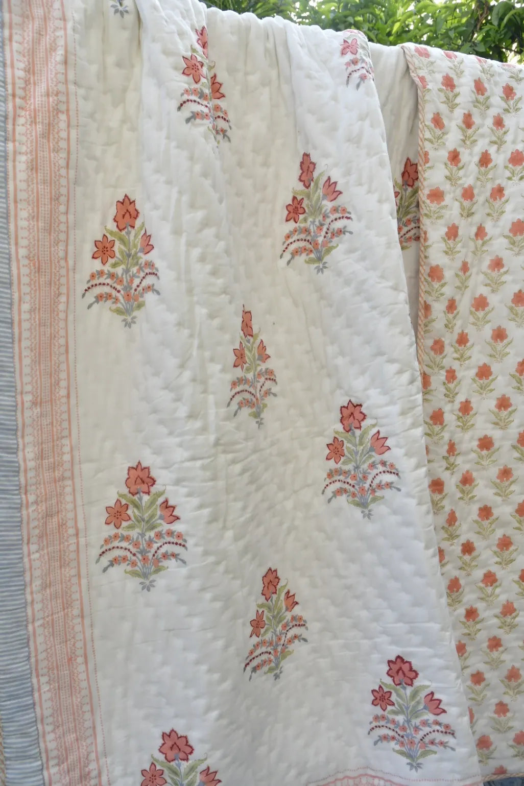 Floral patterned quilt with pink and green flowers on a white background