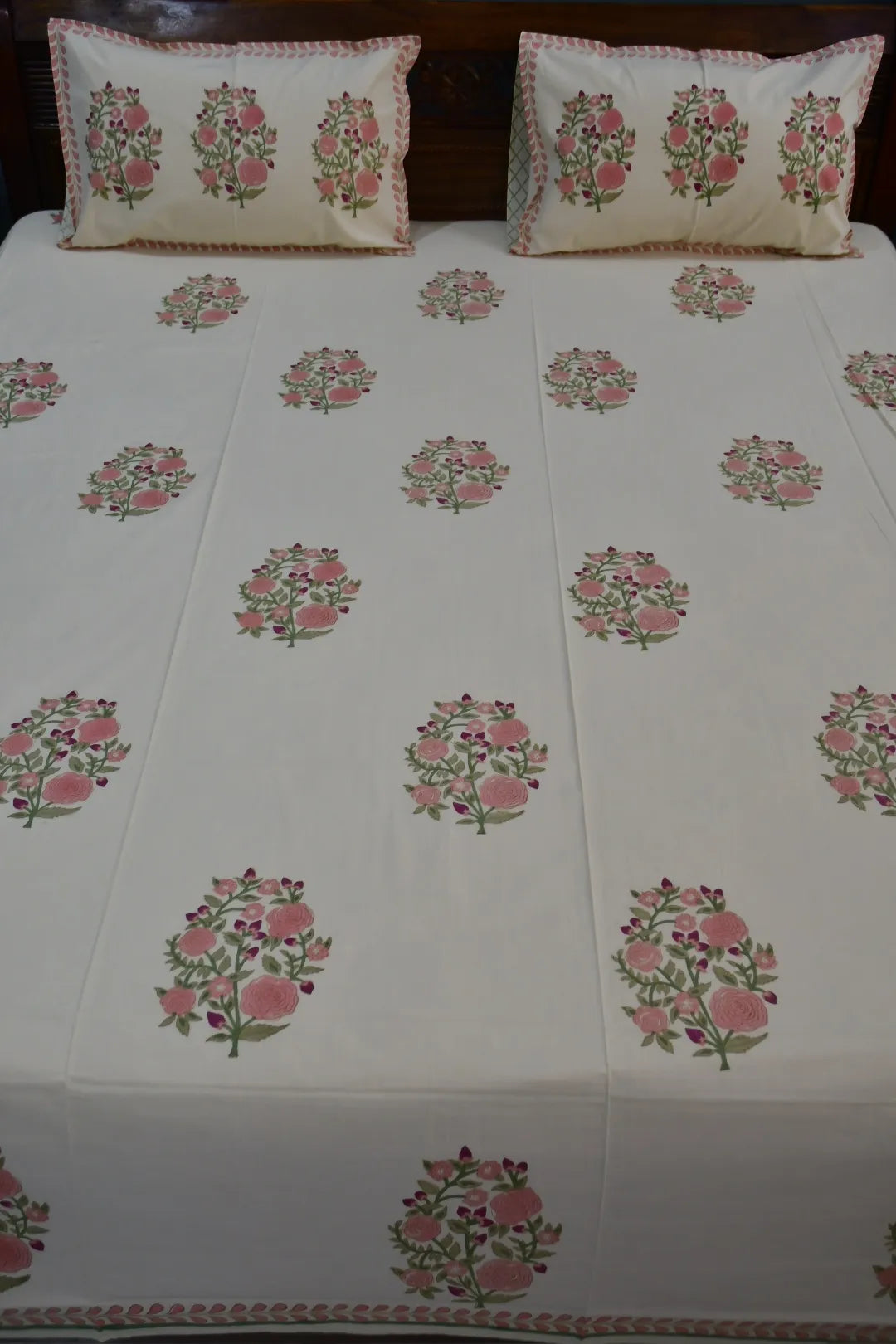 Floral patterned bedding with matching pillows on a bed.
