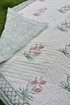 Floral quilt with pink flowers and green leaves on a white background.