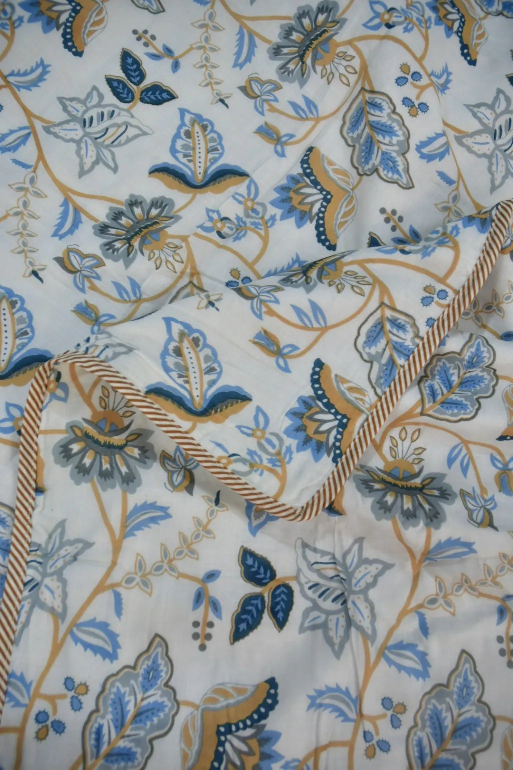 Floral and leaf pattern fabric with blue, brown, and beige colors on a white background