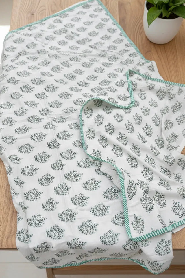 Floral-patterned fabric on a wooden surface with a plant in the background