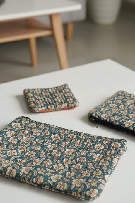 Three floral-patterned pouches on a textured surface with blue floral designs.