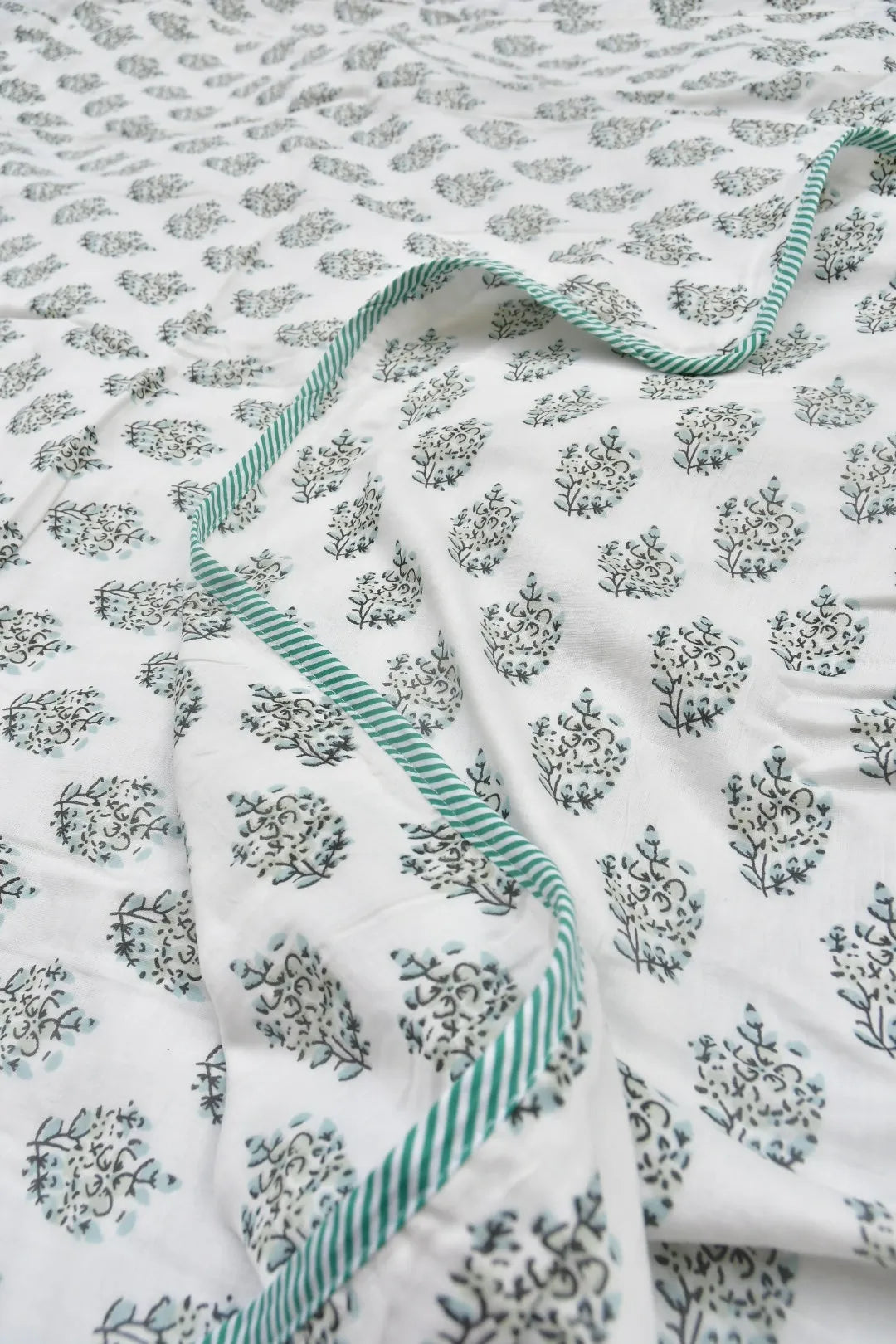Floral patterned blanket with green trim on a white background