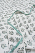Floral patterned blanket with green trim on a white background