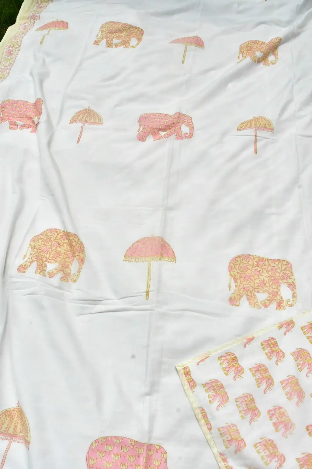 White soft dohar printed with pink elephants and pink umbrellas, with a matching patterned border visible along the top and bottom edges.