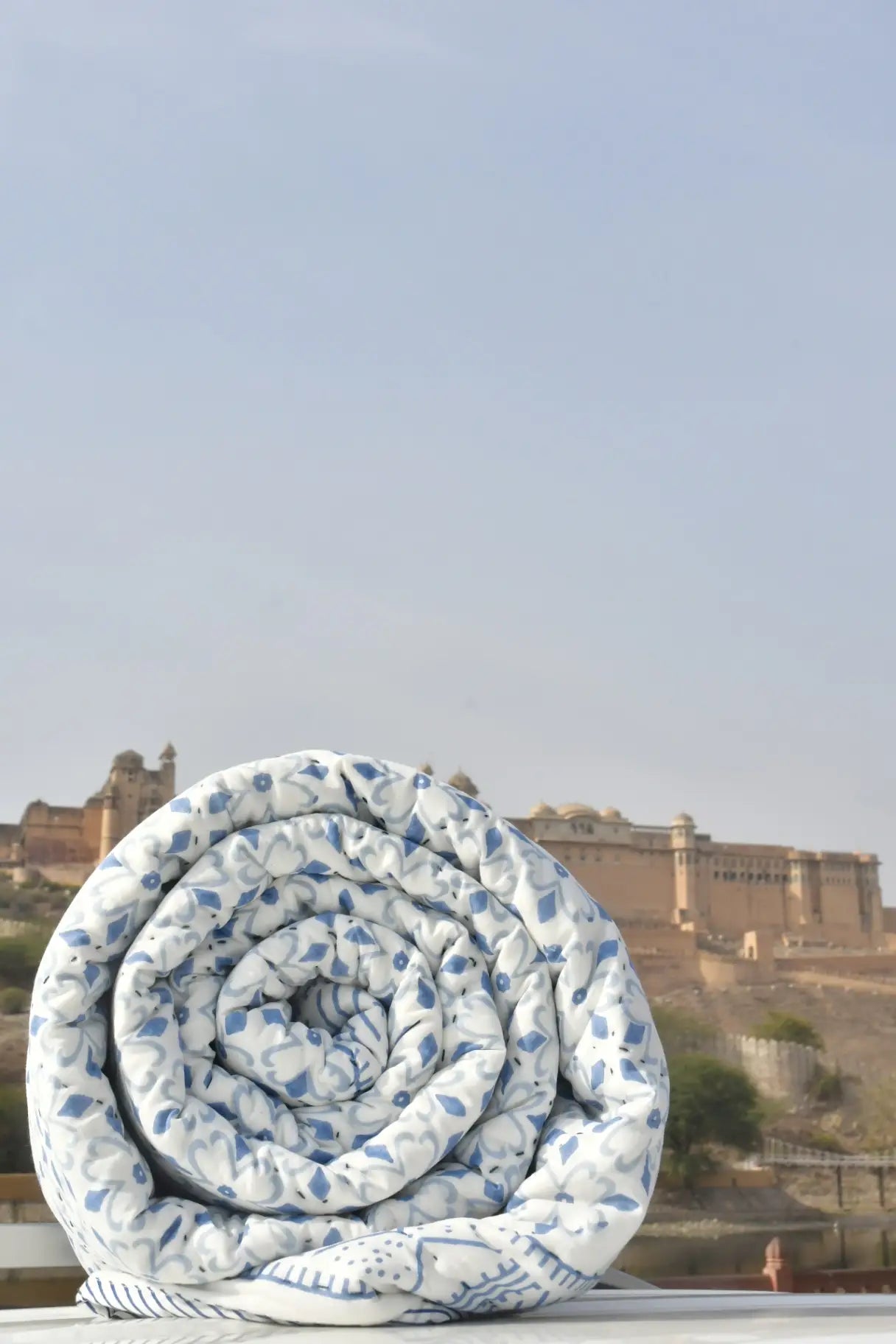 Rolled-up blue and white patterned blanket with a castle in the background