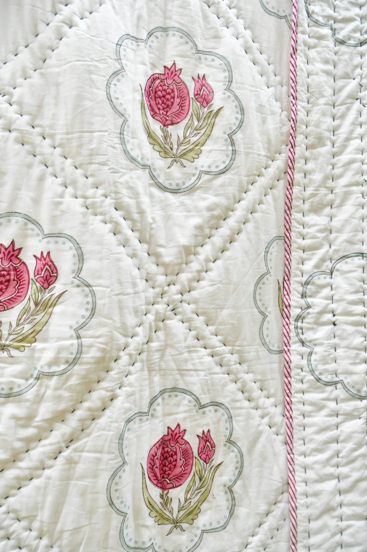 Close-up of a quilt with floral embroidery on a white background