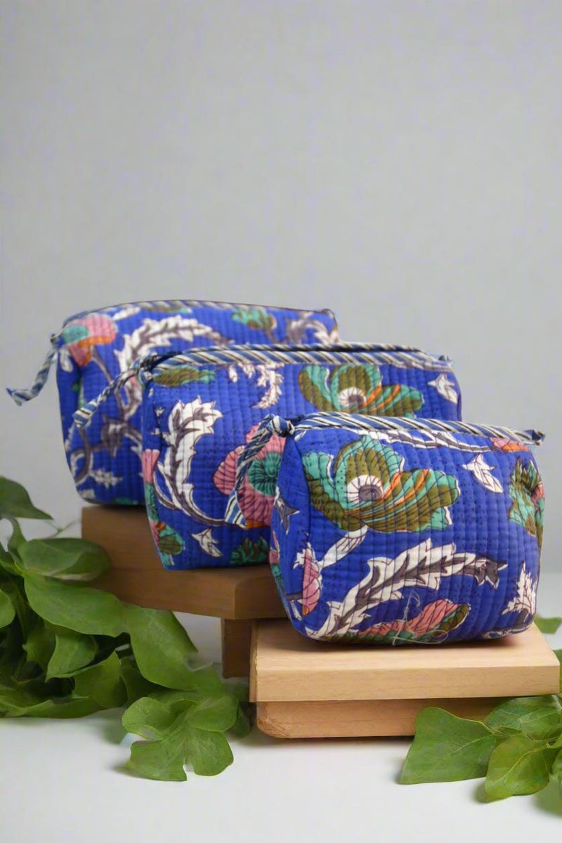 Two blue patterned bags on a wooden stand with green leaves around