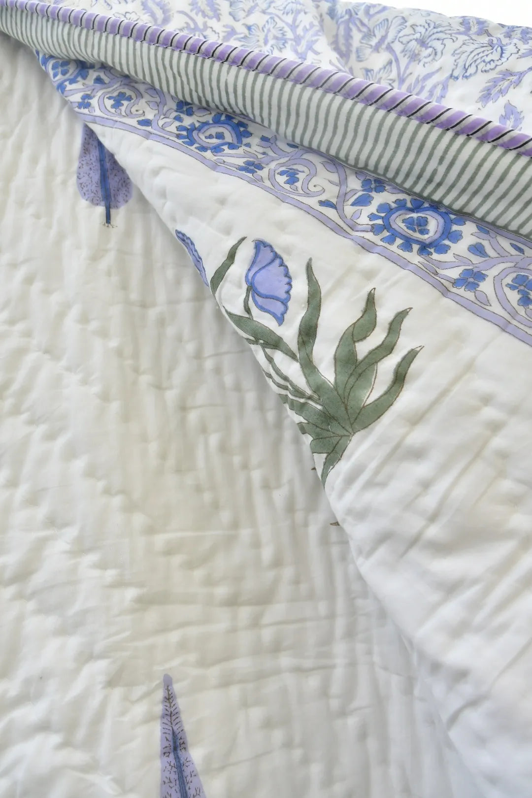 Close-up of a quilt with floral patterns and green leaves on a white background