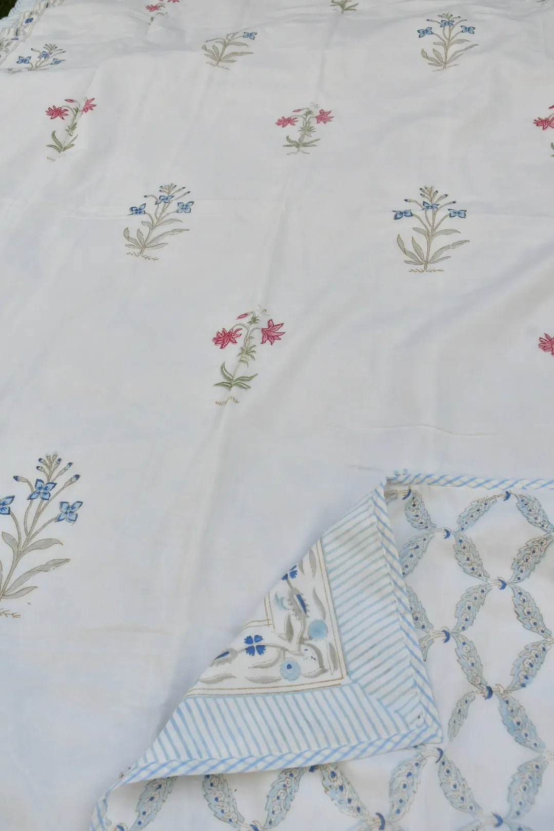 Embroidered fabric with floral patterns and a folded corner on a white background