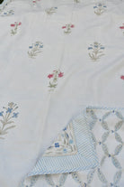 Embroidered fabric with floral patterns and a folded corner on a white background