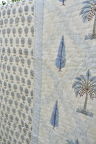 Close-up of a quilt with embroidered palm trees and patterns on a beige background