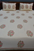 Floral patterned bedding with matching pillows on a wooden bed.