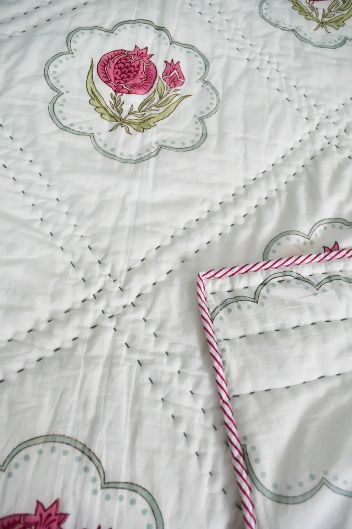 Embroidered Quilt with floral designs and a pink pomegranate on a white background