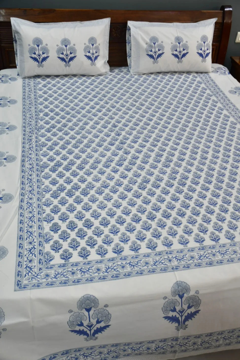 Floral patterned bedspread with matching pillows on a bed.