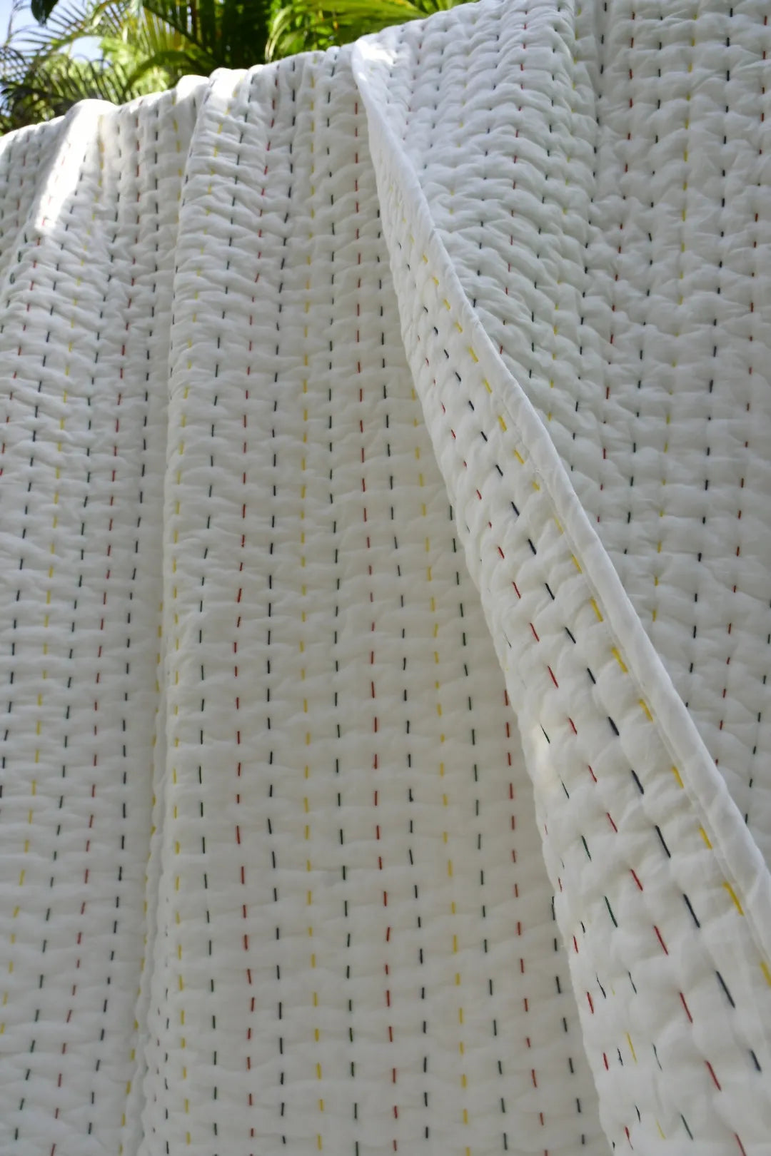 Close-up of a textured white quilt with small colorful dots.