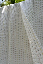 Close-up of a textured white quilt with small colorful dots.