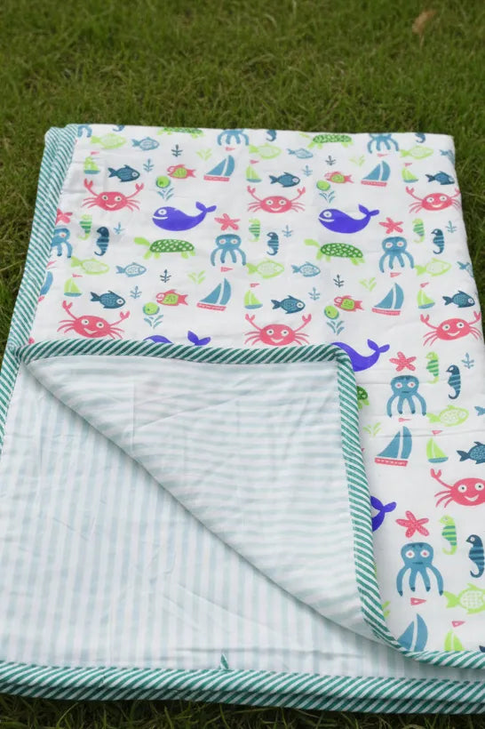 Folded blanket with sea-themed pattern on grass