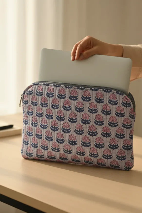 Person holding a laptop in a floral patterned sleeve on a light surface.