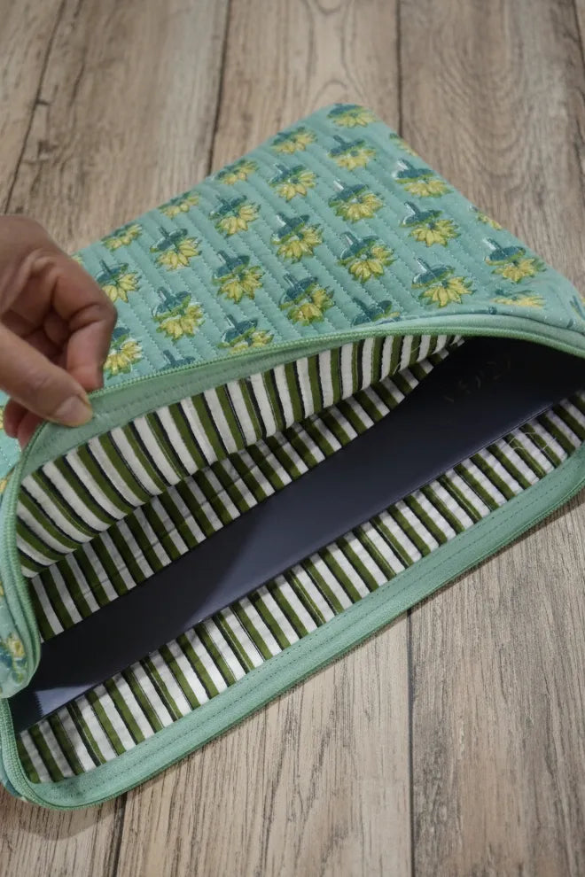 Green fabric laptop sleeve with floral pattern on a wooden surface