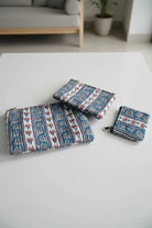 Set of three patterned pouches on a light gray surface with a blurred background