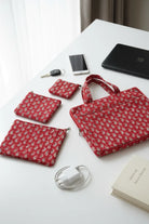 Set of red patterned bags and accessories on a white surface