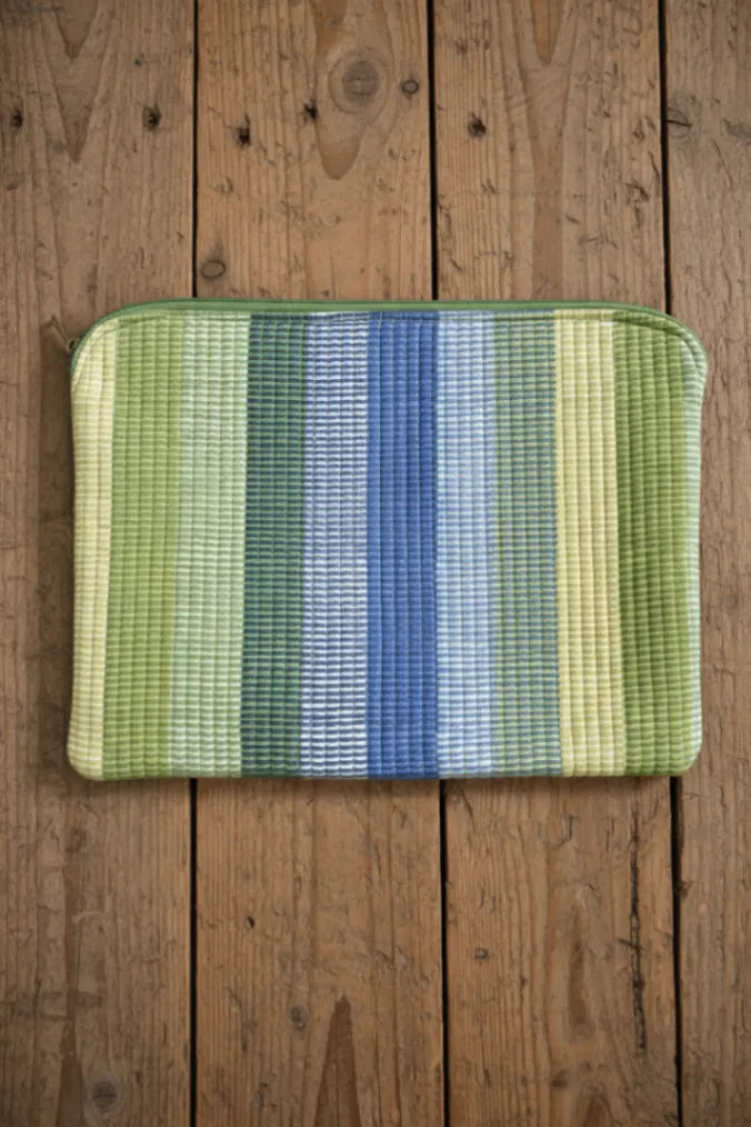 Striped pouch with green, blue, and yellow pattern on a wooden surface