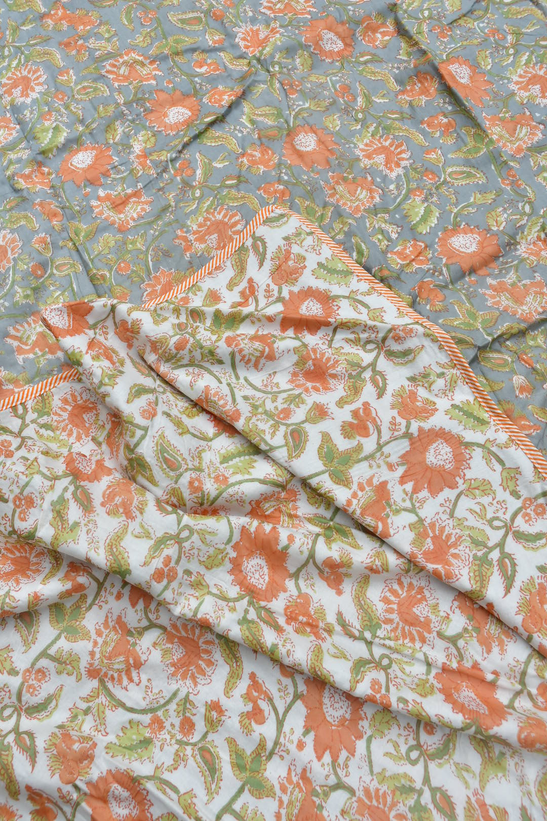 Floral patterned fabric with orange and green flowers on a light background