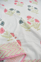 A close-up of a white fabric with a delicate floral print in pink, gray, and sage green, layered over a pink and white chevron-patterned fabric.