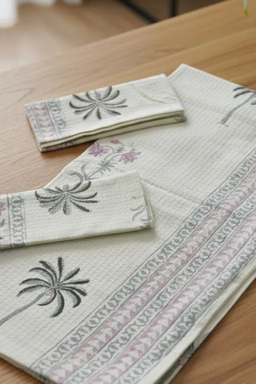 Embroidered fabric with floral and palm tree designs on a wooden surface