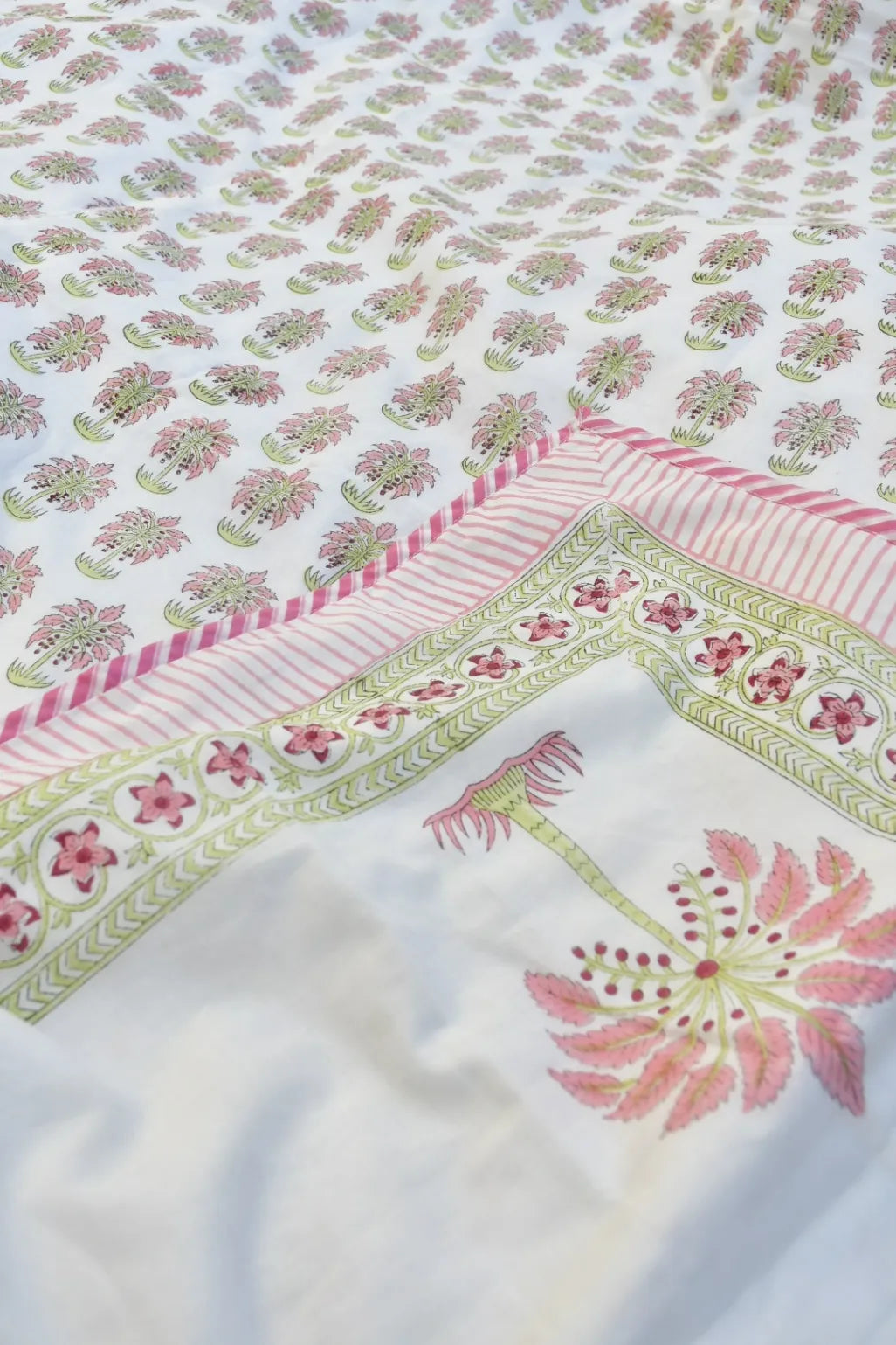 Close-up of a floral patterned blanket with pink and green colors.