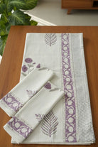 Set of folded towels with floral and leaf patterns on a wooden surface