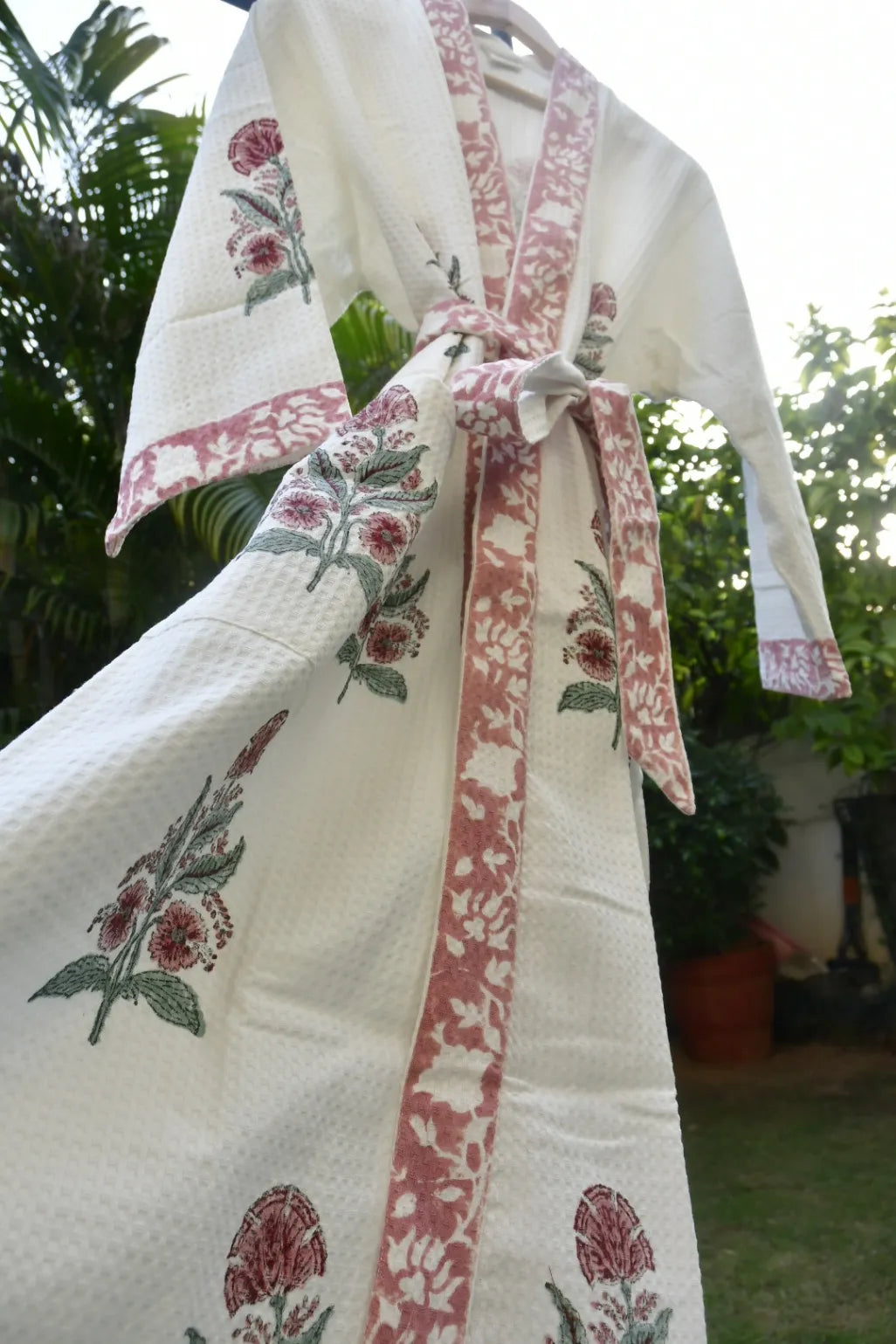 White garment with pink floral patterns hanging outdoors