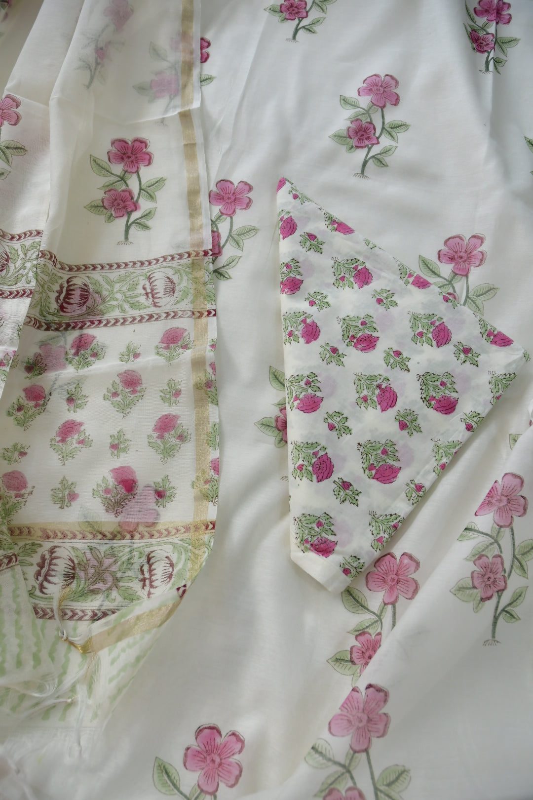 Floral fabric with pink flowers and green leaves on a white background