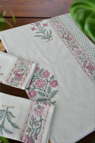 Set of floral patterned napkins on a wooden surface with greenery in the background