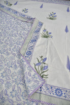 White cotton fabric with blue floral block print and embroidered motifs, featuring a decorative border and striped edge.