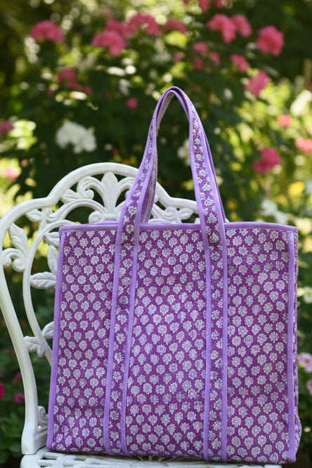 Purple floral-patterned bag on a gray surface with a white background