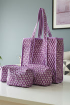 Purple patterned tote bag and pouch on a white surface with a light blue wall in the background.