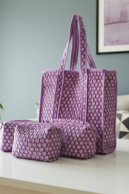 Purple patterned tote bag and pouch on a white surface with a light blue wall in the background.