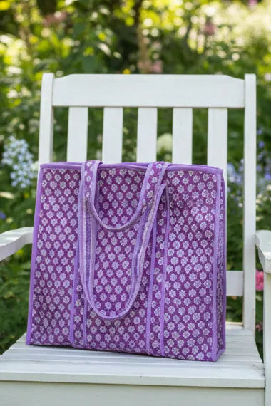Purple patterned bag on a white chair with a garden background