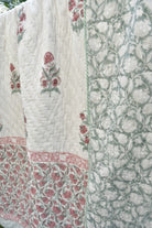 Quilt with floral patterns in pink and green on a white background