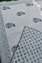 Quilt with floral patterns in blue and green on a white background