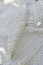 Close-up of white Kantha quilt with colorful thread patterns