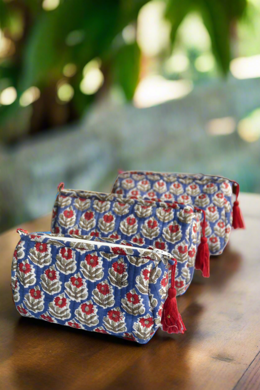 Two floral-patterned pouches with red accents on a wooden surface with a blurred natural background